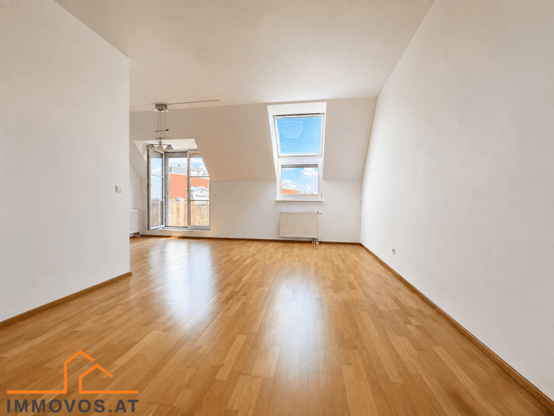 Helles Wohnzimmer mit Dachschrägen, Holzboden und großen Dachfenstern für viel Tageslicht.