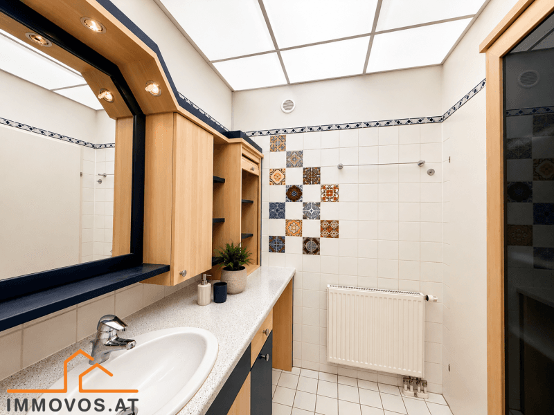 Badezimmer mit Fliesenboden, Badewanne und einem Heizkörper, dekoriert mit bunten Akzentfliesen.