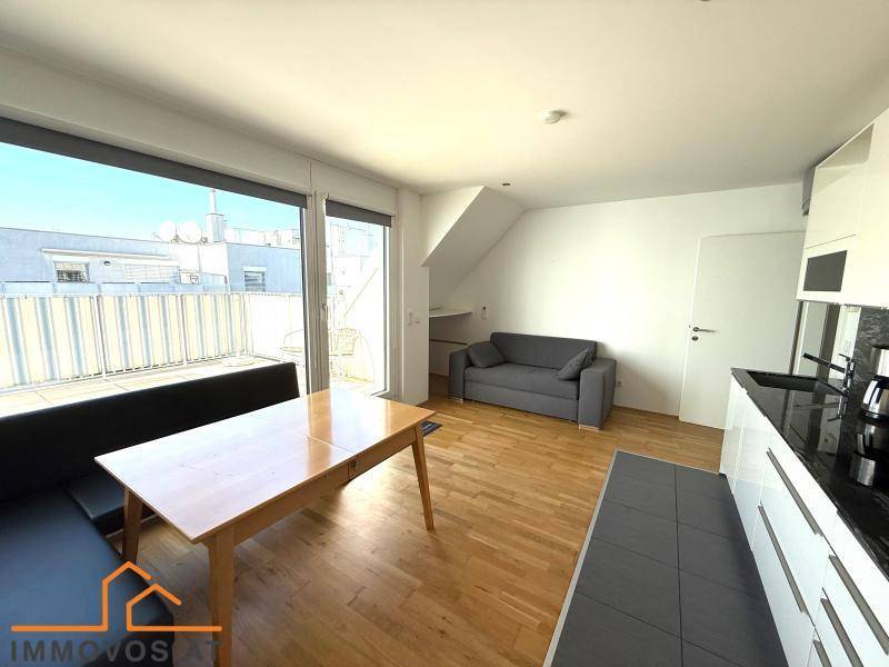 Offener Wohn- und Essbereich mit Holzboden, Sofa und Zugang zur Dachterrasse.