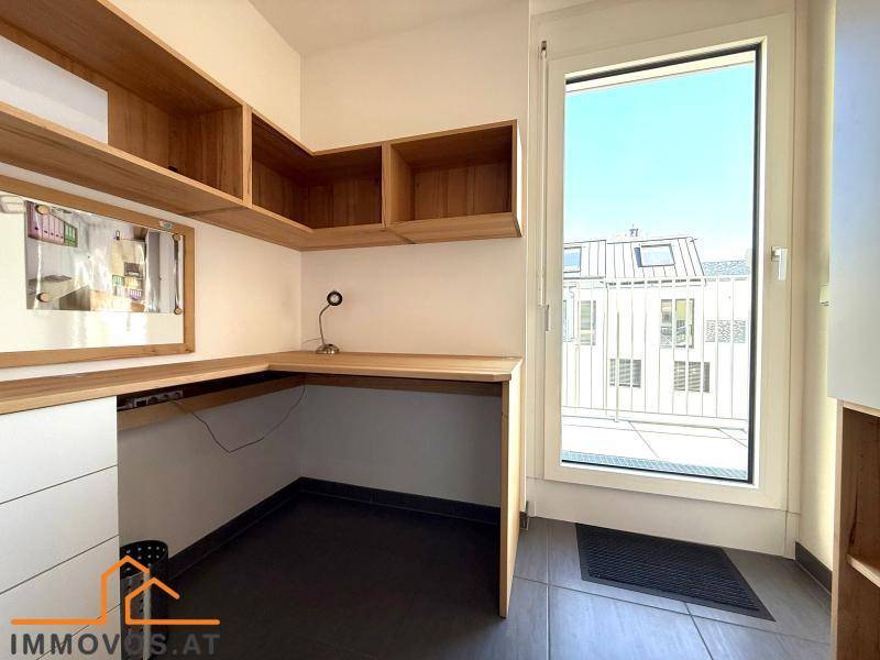 Funktionaler Arbeitsbereich mit Holzregalen, Schreibtisch und Zugang zu einem Außenbereich.