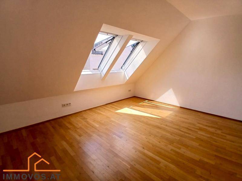 Lichtdurchfluteter Dachbodenraum mit Holzboden und schrägen Wänden, ideal für ein Schlafzimmer oder Büro.
