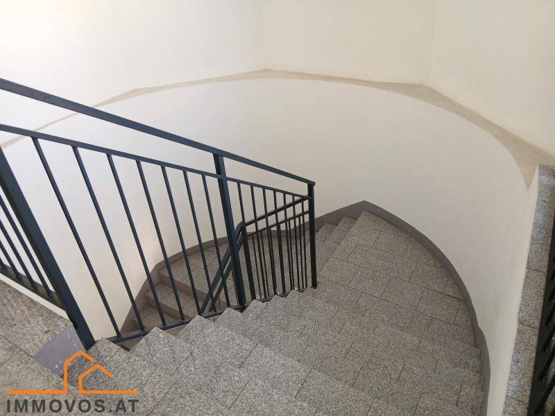 Treppenhaus mit Granitstufen und schwarzem Metallgeländer in einem Mehrfamilienhaus, gut erhalten.