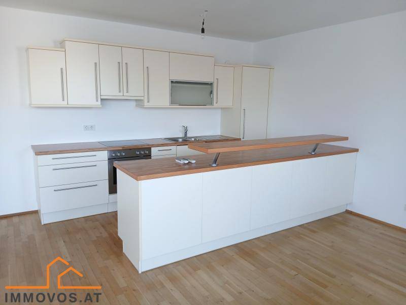 Moderne Einbauküche mit Holz-Arbeitsplatte und integriertem Kochfeld in einem hellen, offenen Raum.