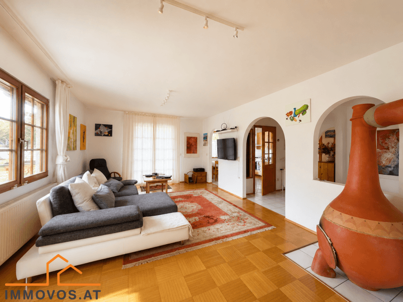 Helles Wohnzimmer mit Parkettboden, gemütlichem Sofa und einem dekorativen Kaminofen.