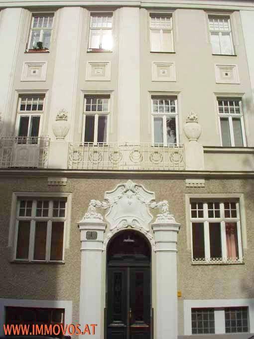 Detailansicht einer eleganten Gebäudefassade mit kunstvollem Eingangsbereich und schmiedeeisernem Balkon.