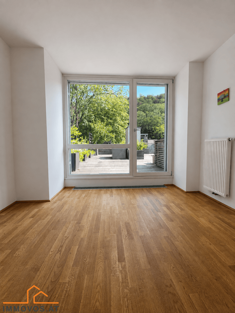 Helles Schlafzimmer mit Holzboden und großen Fenstern, die zur Dachterrasse führen.