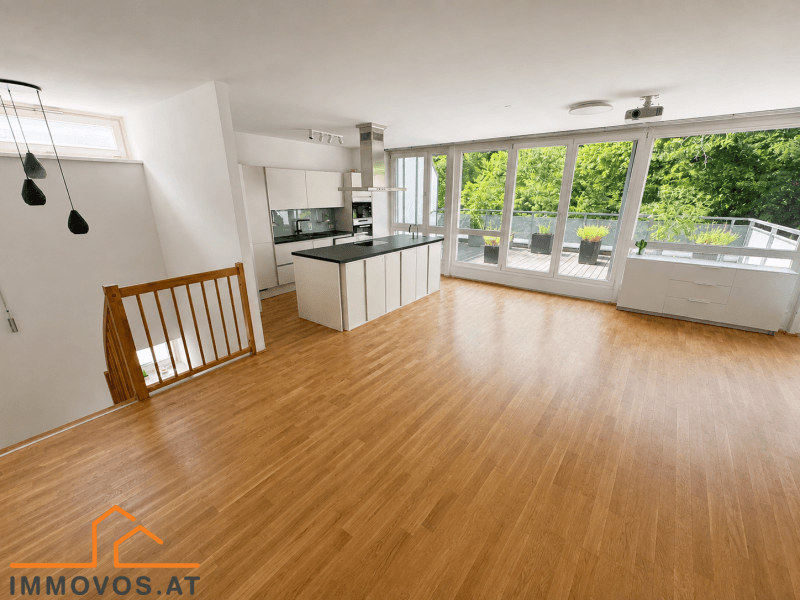 Geräumiger offener Wohn-Essbereich mit Holzboden und großen Fenstern zur Dachterrasse.