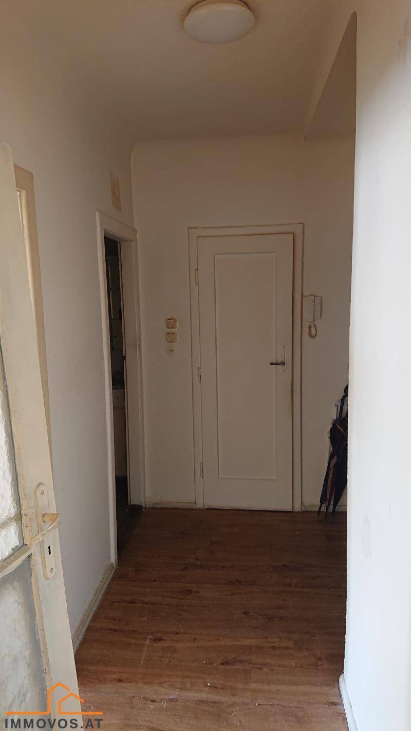 Heller Flur mit Holzboden und weißen Türen, der verschiedene Räume verbindet.