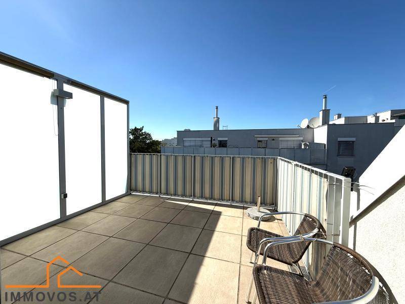 Geräumige Dachterrasse mit Fliesenboden und Blick auf die umliegenden Gebäude.
