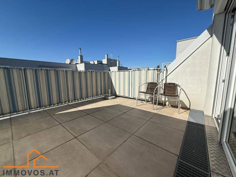 Sonnige Dachterrasse mit Fliesenboden und Sichtschutz, ideal zum Entspannen im Freien.