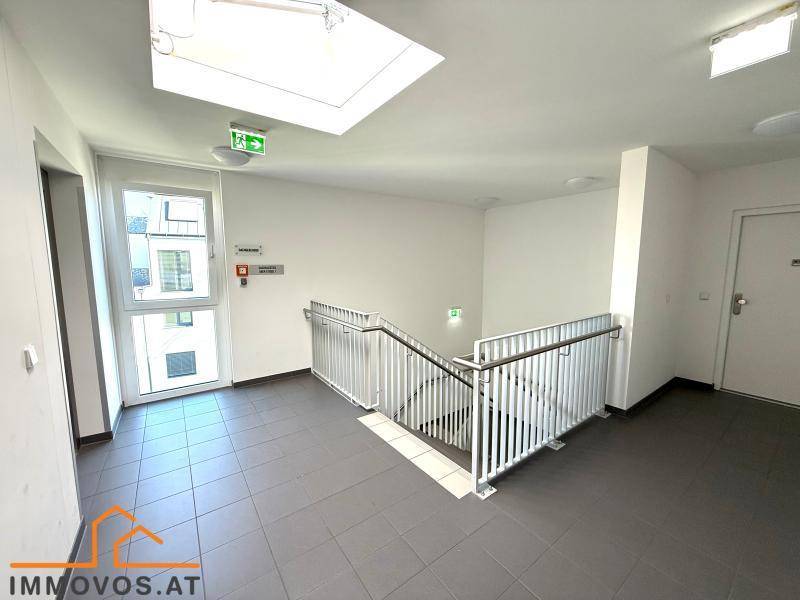 Heller Treppenaufgang mit Fliesenboden und Tageslicht durch ein Dachfenster.