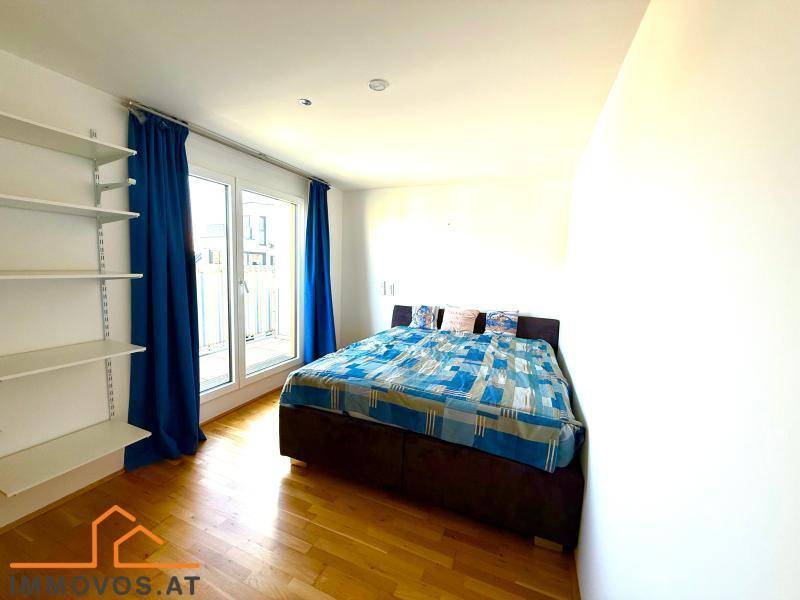 Schlafzimmer mit Holzboden, großem Bett und Zugang zu einem Balkon oder einer Terrasse.