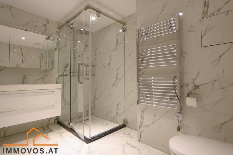 Modernes Badezimmer mit Marmorfliesen, begehbarer Dusche und beheiztem Handtuchhalter.