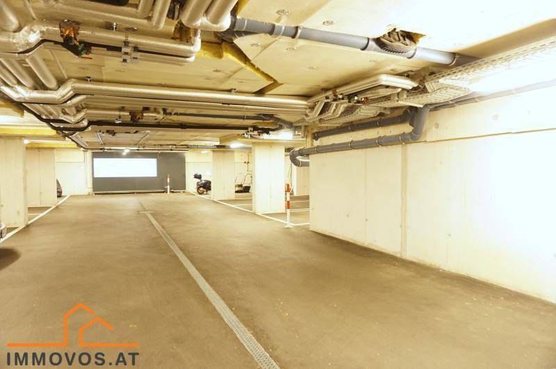Geräumige Tiefgarage mit markierten Stellplätzen und sichtbaren Versorgungsleitungen an der Decke.
