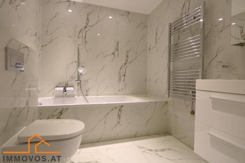 Elegantes Badezimmer mit Badewanne, Marmorfliesen und wandmontiertem WC.