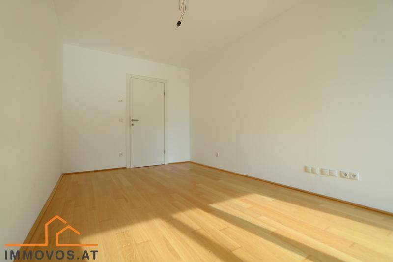 Leeres Zimmer mit hellem Parkettboden und einer weißen Tür, bereit zur individuellen Gestaltung.