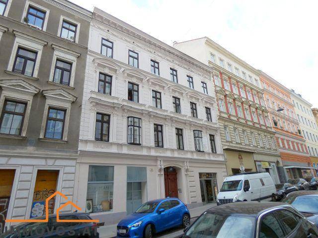 Historisches Gebäude mit klassischer Fassade und großen Fenstern an einer belebten Stadtstraße.