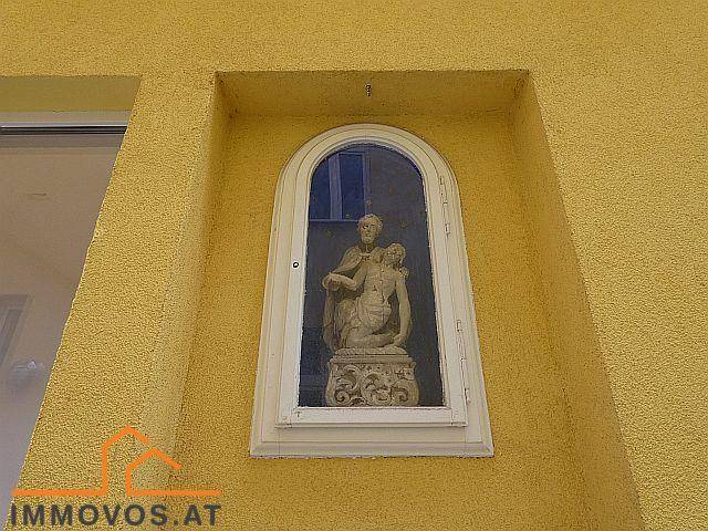 Eine Nische in der gelben Fassade mit einer religiösen Statue, die dem Gebäude Charakter verleiht.