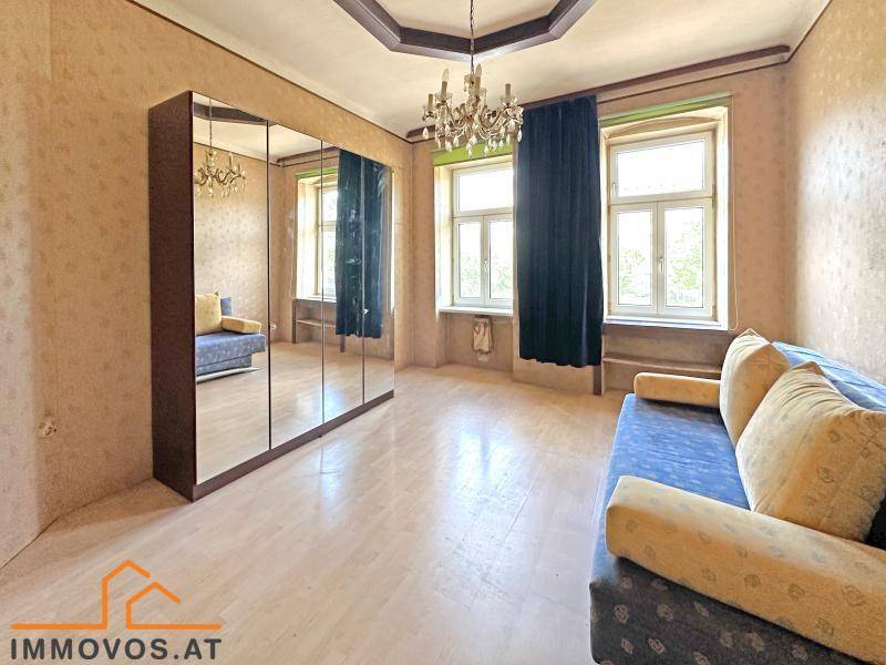 Schlafzimmer mit hellem Boden, großem Spiegelschrank und Kronleuchter, bietet viel Stauraum.