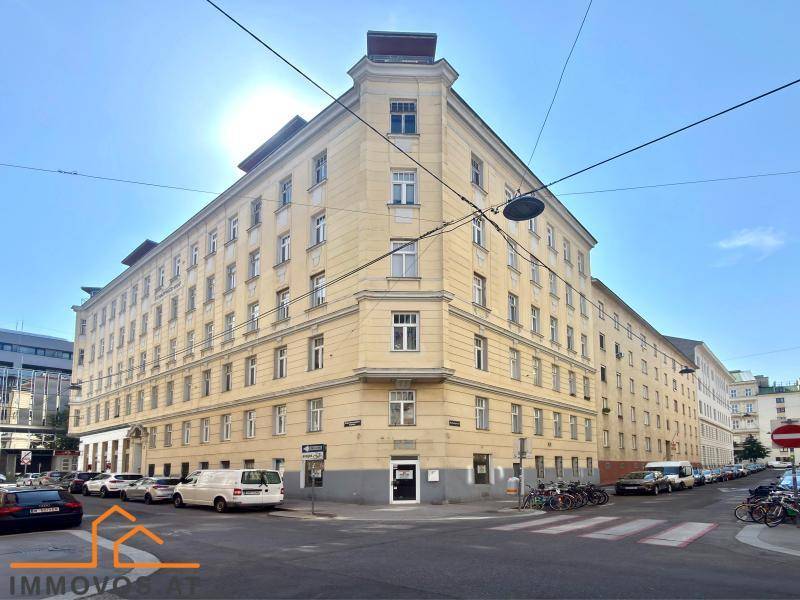 Großes Eckgebäude in städtischer Umgebung mit vielen Fenstern und klassischer Architektur.