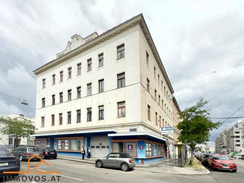 Eckgebäude in städtischer Umgebung mit Geschäften im Erdgeschoss und Wohnungen darüber.