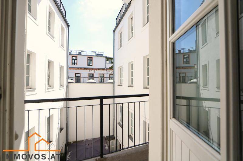 Blick vom Balkon in den ruhigen Innenhof, umgeben von weißen Gebäudefassaden.