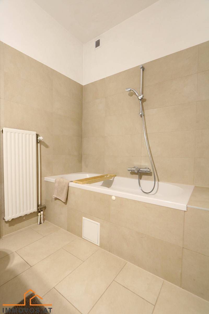 Badezimmer mit Badewanne und beigefarbenen Fliesen, bietet Raum für Entspannung.