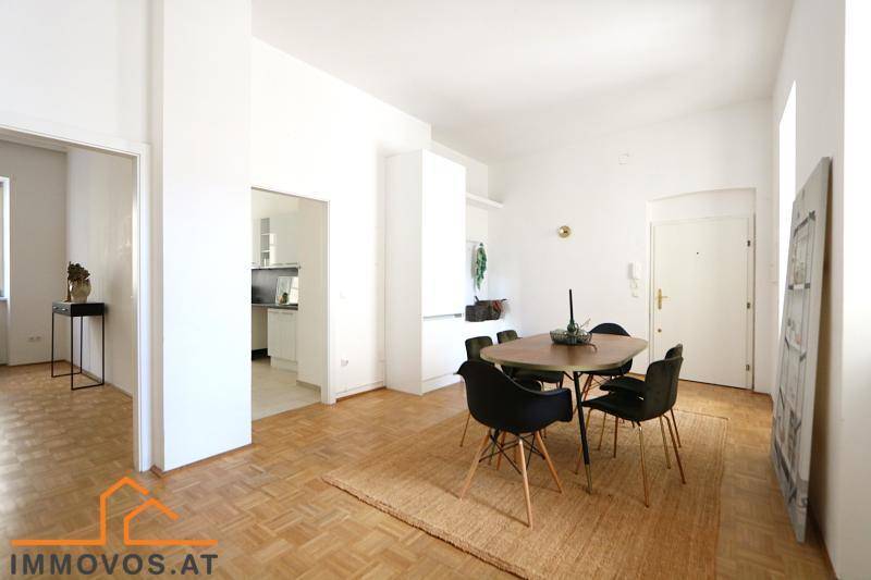 Heller Essbereich mit Holztisch und schwarzen Stühlen, Parkettboden und Zugang zur Küche.