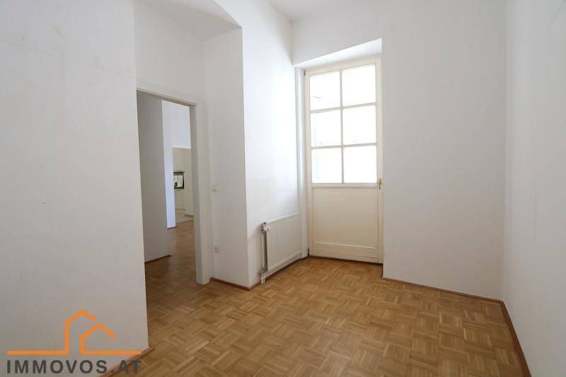 Leerer Raum mit Parkettboden und Zugang zu einem Balkon, bietet flexible Nutzungsmöglichkeiten.