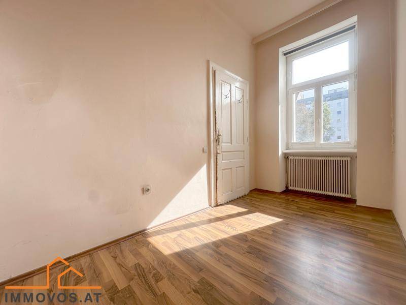 Gemütliches Schlafzimmer mit Holzdielenboden und einem großen Fenster, das viel Licht hereinlässt.