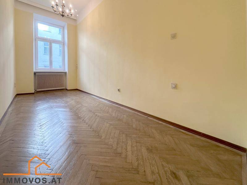 Geräumiges Zimmer mit klassischem Fischgrätparkett und einem großen Fenster für viel Tageslicht.