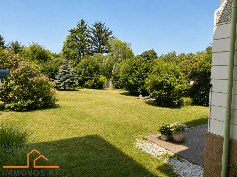 Großer, gepflegter Garten mit weitläufiger Rasenfläche und altem Baumbestand an einem sonnigen Tag.