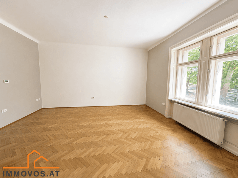 Geräumiges, leeres Zimmer mit Fischgrätparkett und großen Fenstern, bereit zur individuellen Gestaltung.