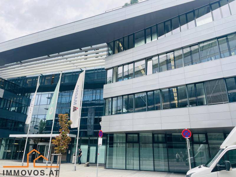 Ansicht der modernen Bürogebäude-Fassade mit reflektierenden Fenstern und einem Eingangsbereich mit Fahnenmasten.