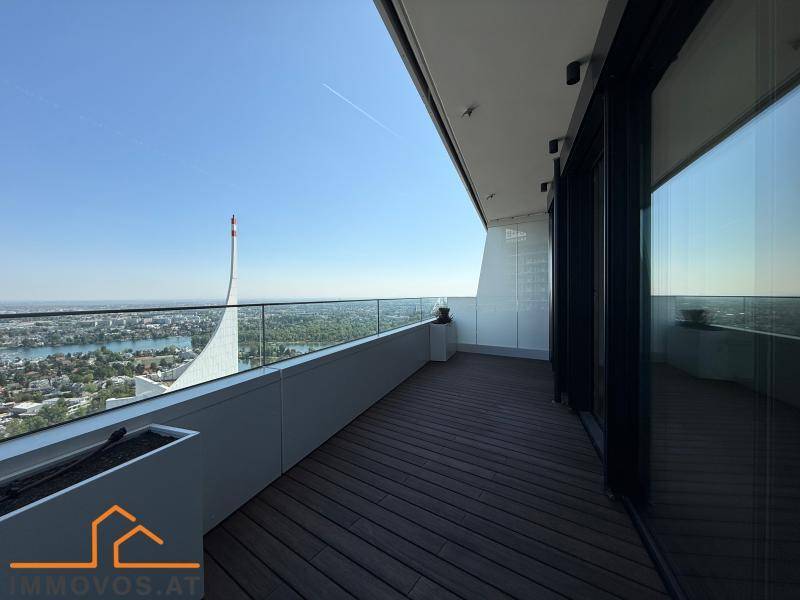 Geräumiger Balkon mit Holzboden und Glasgeländer bietet einen weiten Blick über die Stadt und den See.