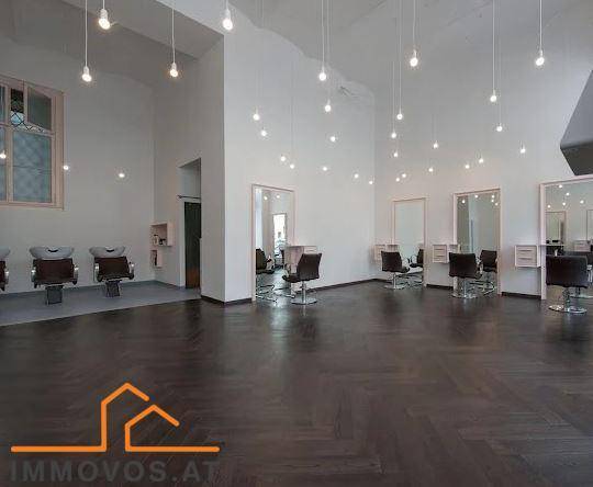 Heller Friseursalon mit hohen, gewölbten Decken, vielen Pendelleuchten und dunklem Holzboden.
