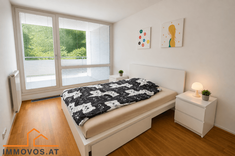 Gemütliches Schlafzimmer mit weißem Bett, Nachttischen und großen Fenstern mit Jalousien.