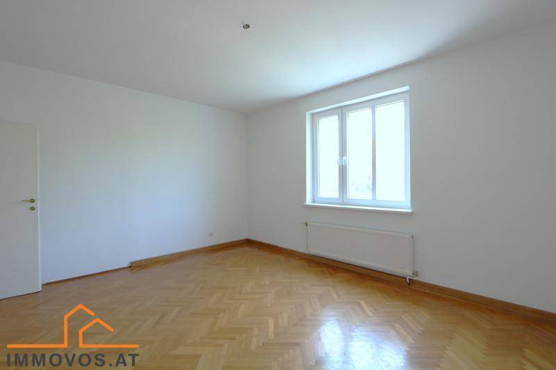 Helles Schlafzimmer mit klassischem Fischgrätparkett und großem Fenster.