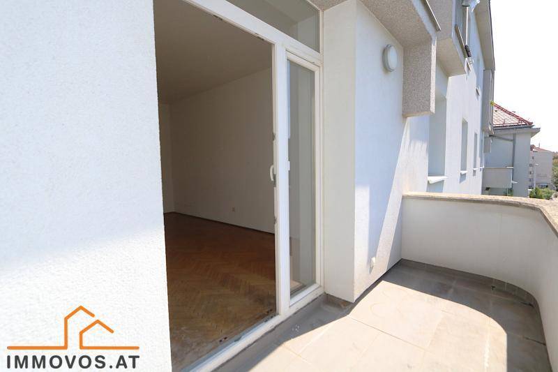 Balkon mit Fliesenboden und Zugang zu einem hellen Innenraum, umgeben von Grün.