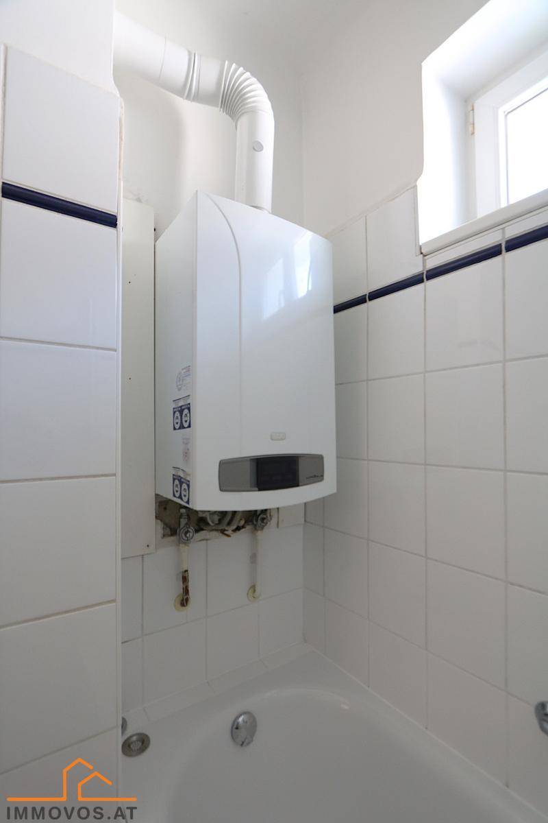 Badezimmer mit Gastherme über der Badewanne und kleinem Fenster.