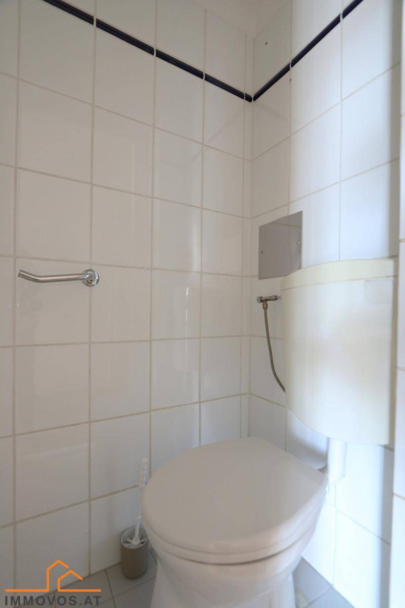 Separate Toilette mit Wandfliesen und einfacher Ausstattung.