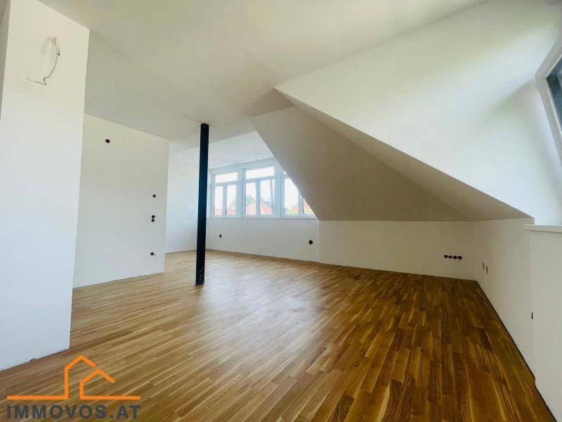 Heller Dachgeschossraum mit schrägen Wänden, Holzboden und großen Fenstern, bereit zum Ausbau.