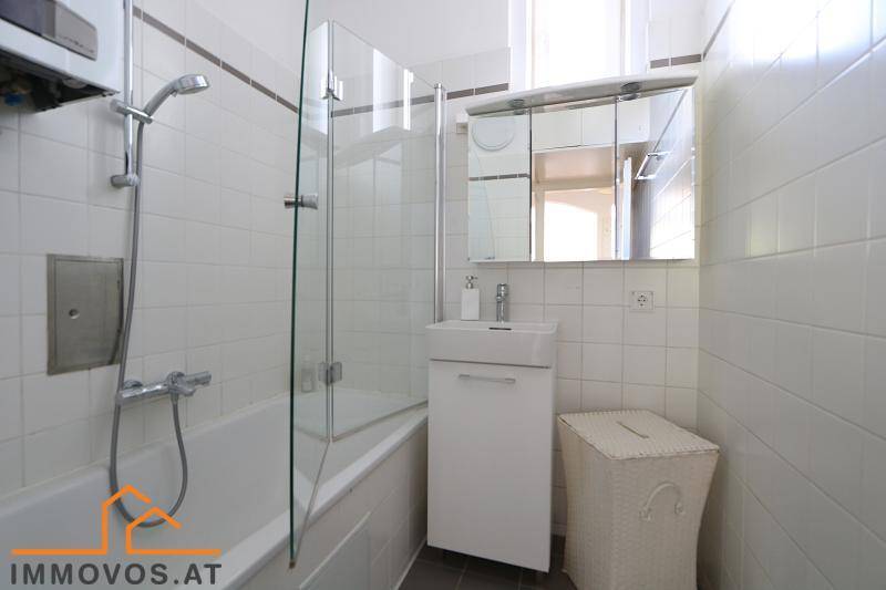 Badezimmer mit Badewanne, Duschabtrennung, Waschbecken und Spiegelschrank.