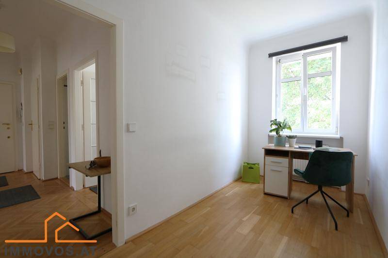 Helles Arbeitszimmer mit Schreibtisch, Parkettboden und Fenster.
