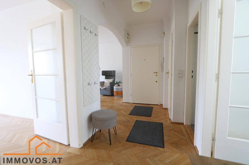 Heller Flur mit Fischgrätparkett, Garderobe und Zugang zu den Zimmern.