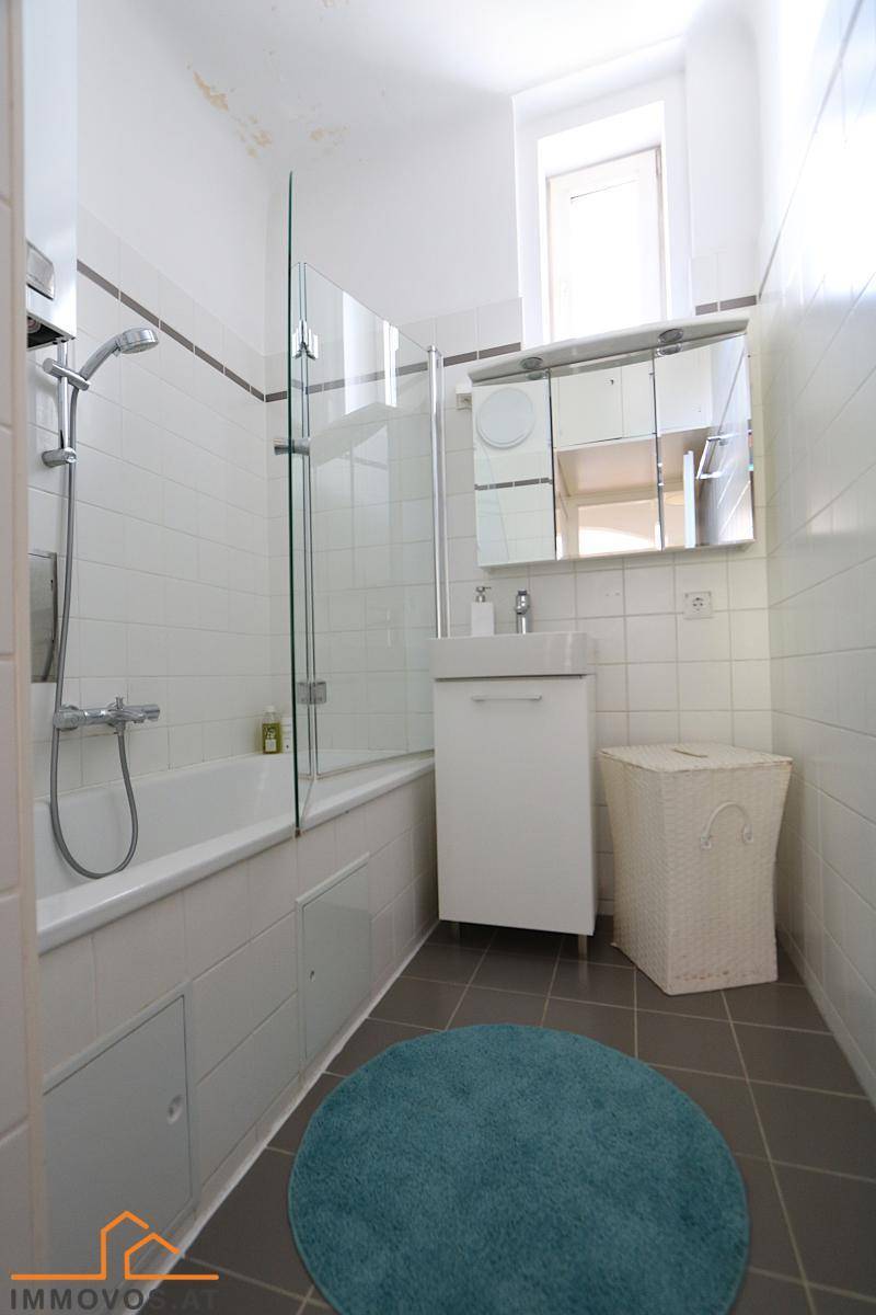 Modernes Badezimmer mit Badewanne, Duschabtrennung und kleinem Fenster.