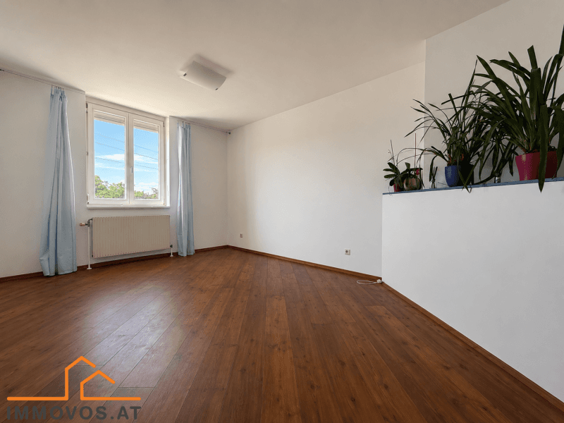 Helles Schlafzimmer mit Laminatboden und Fenster, bereit für individuelle Einrichtungsideen.