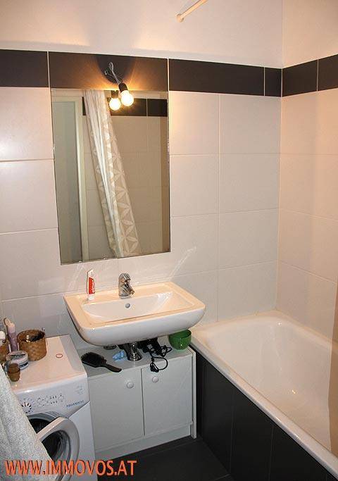 Modernes Badezimmer mit Badewanne, Waschbecken und Waschmaschine.