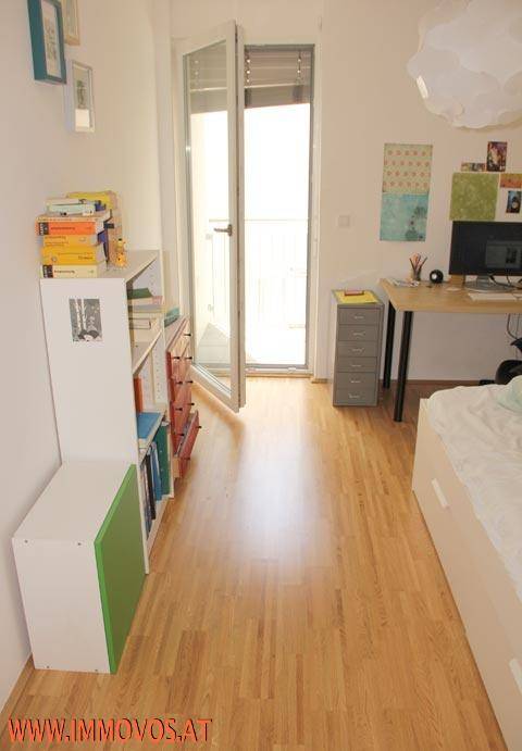 Schlafzimmer mit Zugang zum Balkon, Holzfußboden und einem Arbeitsbereich.