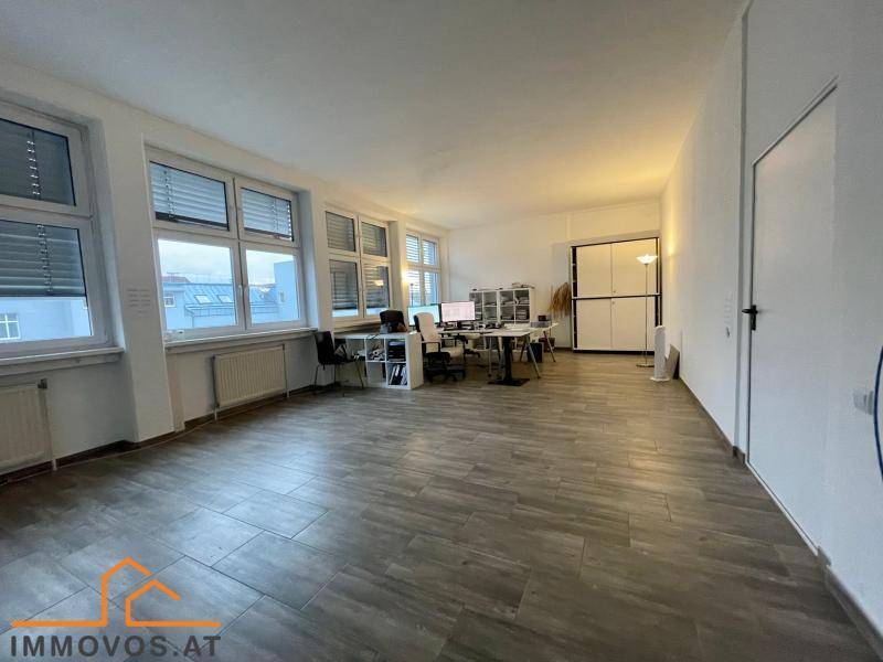 Großer, heller Büroraum mit mehreren Arbeitsplätzen, großen Fenstern und modernem Laminatboden.